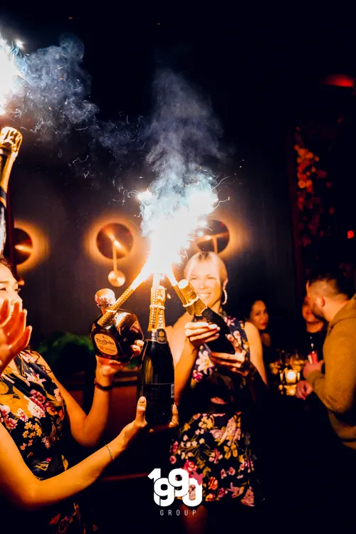 3 host girls taking bottles to a 1990 group vip experience.