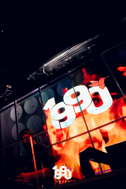 DJ booth with the 1990 Group logo lighting up the dance floor at Fuego Thursdays rooftop party.