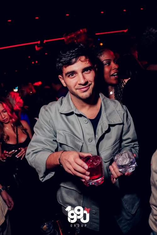 Man holding drinks while enjoying the energetic atmosphere at Fuego Thursdays' Latin rooftop party in Manhattan.