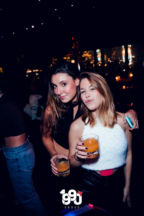 Two friends enjoying drinks and nightlife at Fuego Thursdays' Latin rooftop event in New York City.