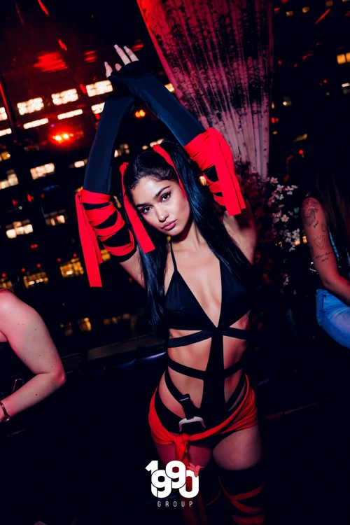 Woman dancing in a red and black costume at Fuego Thursdays rooftop party.