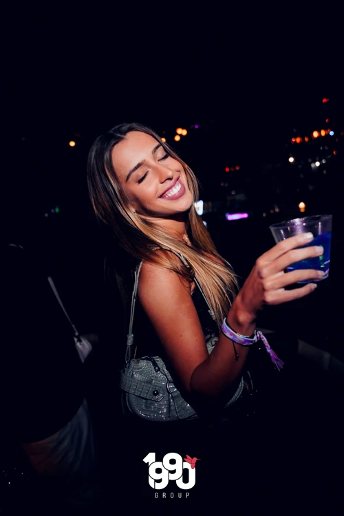 Woman smiling while holding a drink at Fuego Thursdays Latin party in NYC